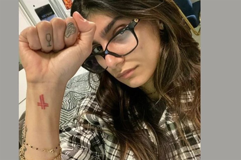 Mia Khalifa tattoos: red wrist cross and tiny hand symbols