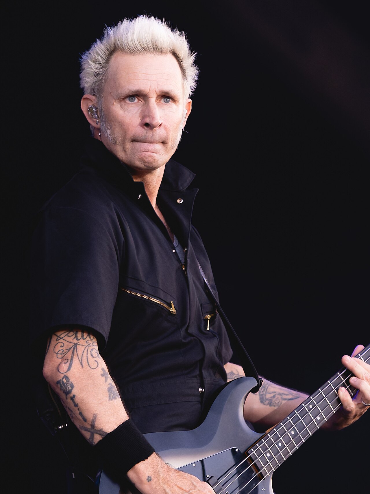 Mike Dirnt tattooed arms in a close-up performance photo