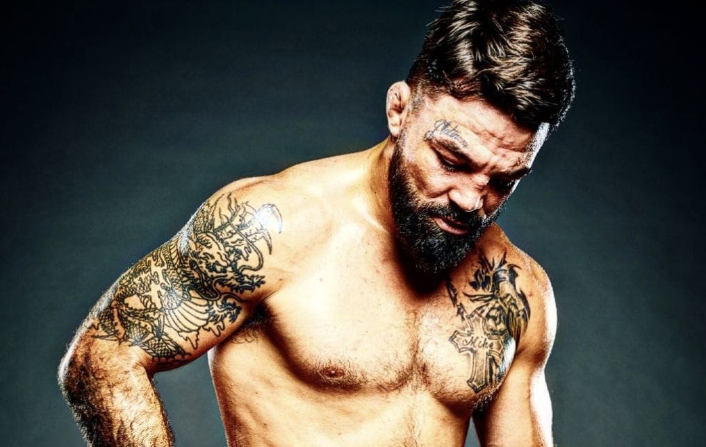 Mike Perry showing his dragon arm and chest tattoos