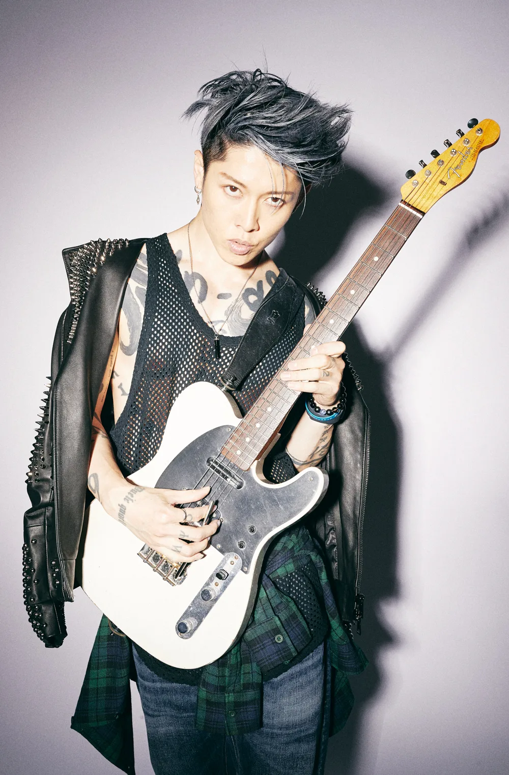 Miyavi playing guitar with visible chest and wrist tattoos
