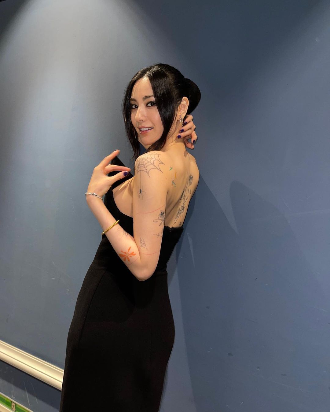 Nana tattoos: genuine tattoo photograph showing varied motifs across Nana’s shoulders, arms and legs