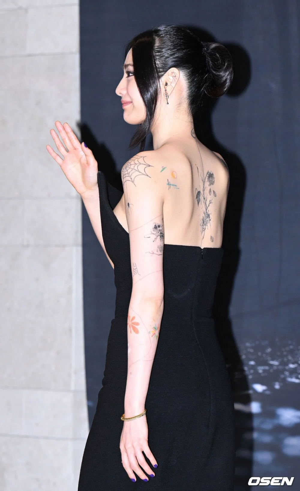 Nana tattoos: rear-view VIP screening photograph showing the upper-back flower and surrounding designs