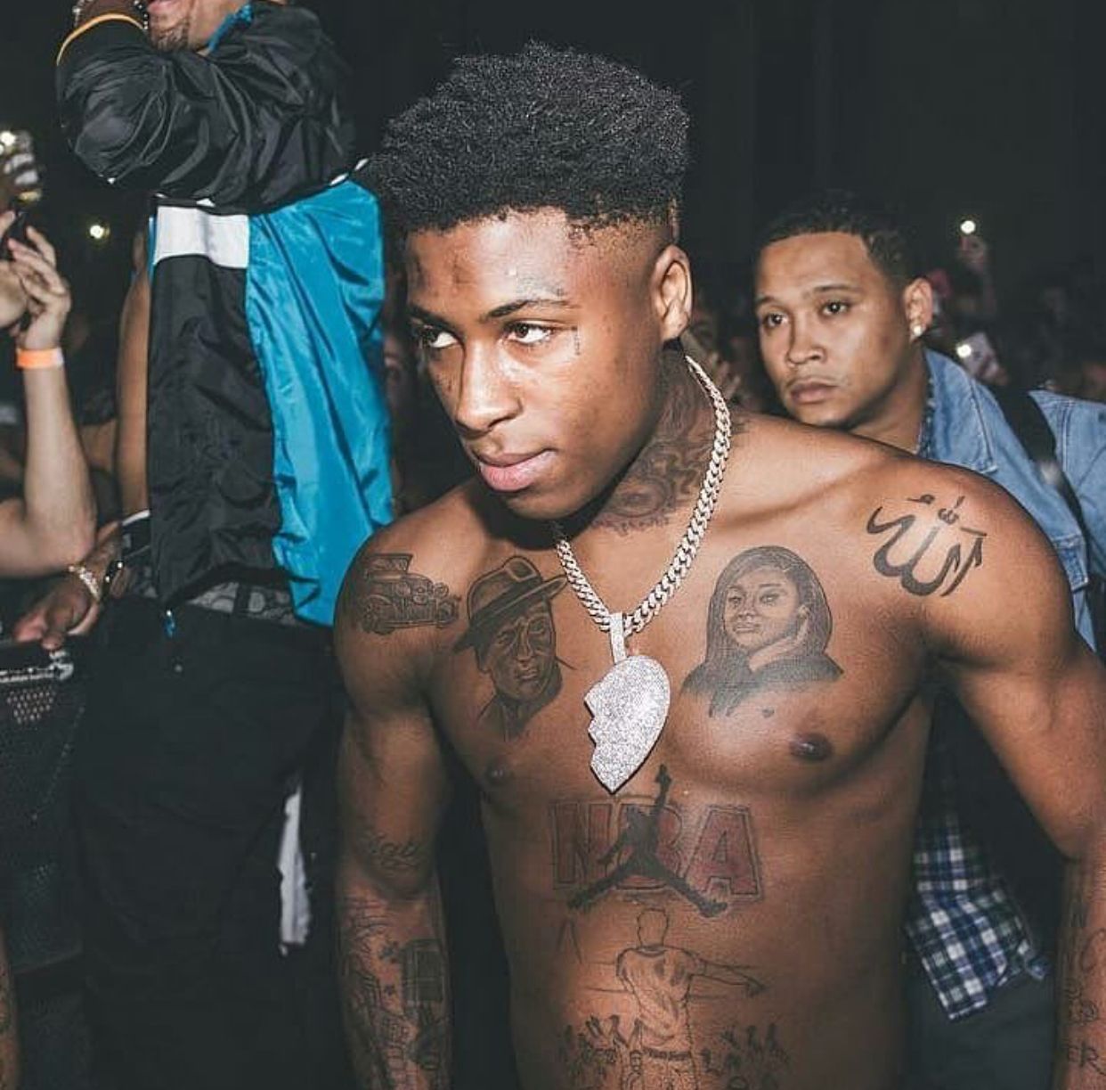 NBA YoungBoy’s chest, shoulder and forearm tattoos in a close crowd photo