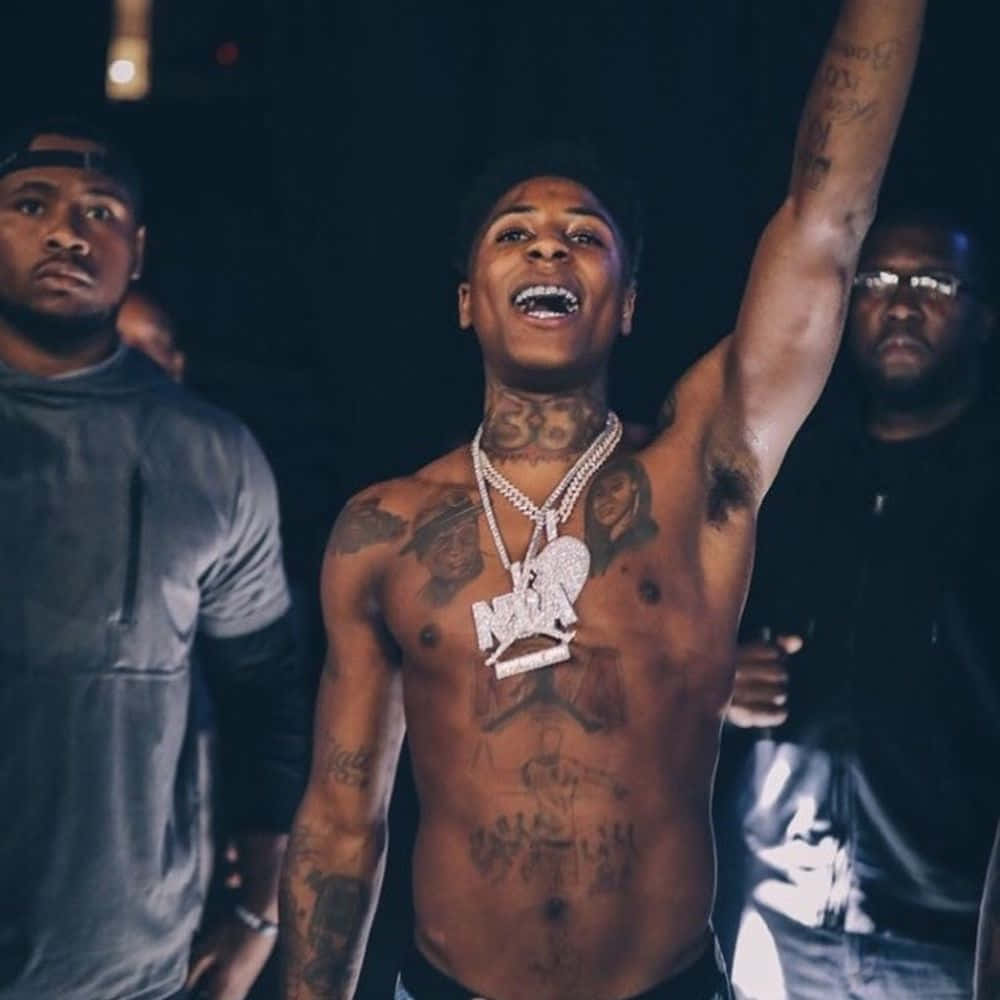 NBA YoungBoy showing his chest and arm tattoos during a live performance