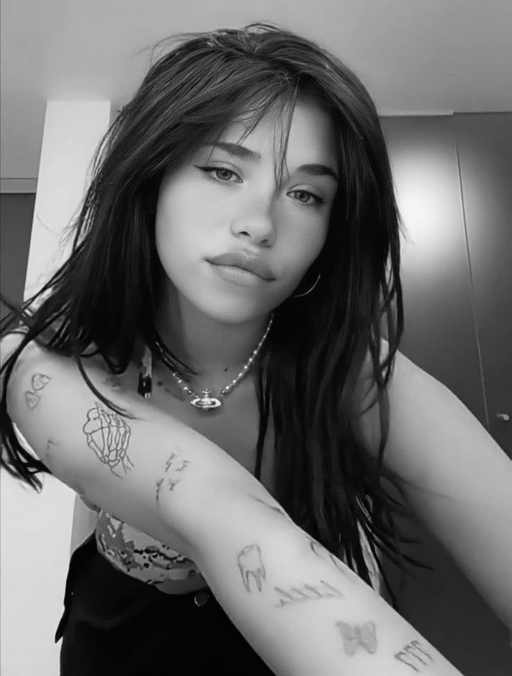 Nessa Barrett tattoos: skeletal hand, tooth, birds, and small forearm symbols