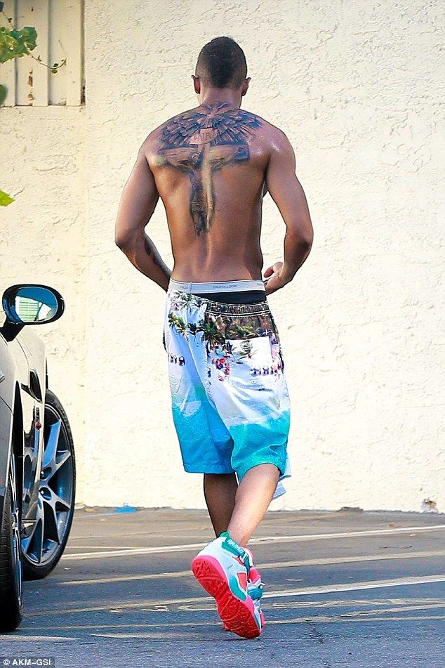 Nick Cannon tattoos: full back crucifix and winged cover-up tattoo photographed after the old name ink was replaced