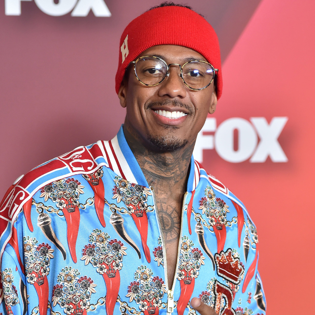 Nick Cannon tattoos: visible neck tattoo and layered upper-chest ink in a sharp event portrait