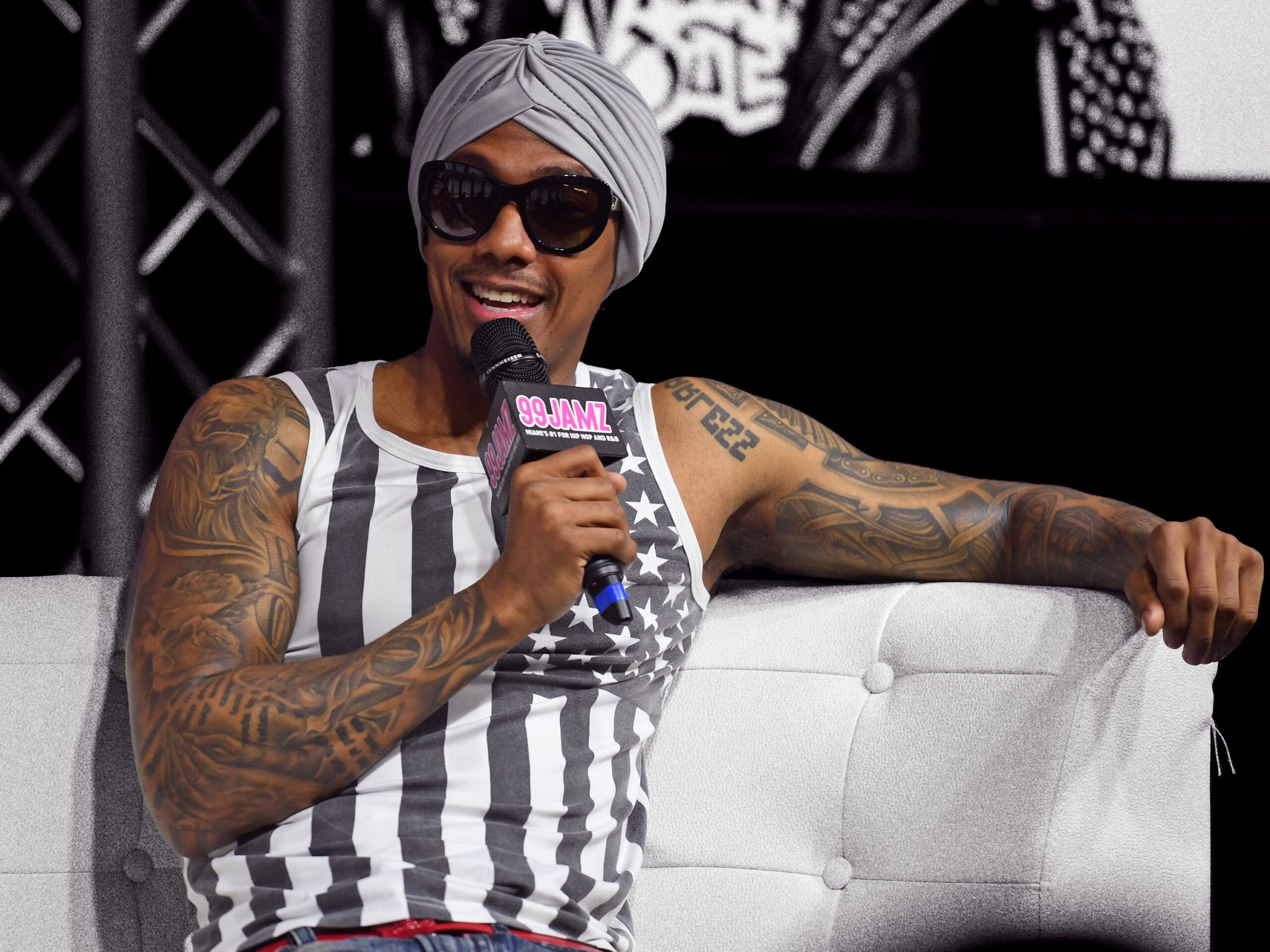 Nick Cannon tattoos: wide event portrait showing the extensive arm tattoos that support his digital and analog sleeve themes