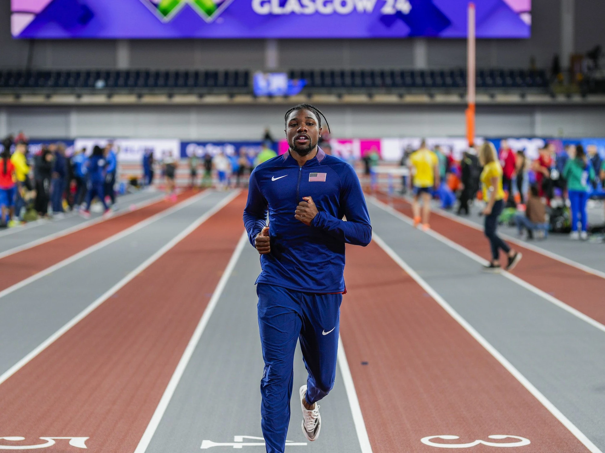 Noah Lyles in a contextual photograph: Contextual photograph of Lyles in his blue track kit at an indoor competition; it does not show tattoo evidence.; not tattoo evidence