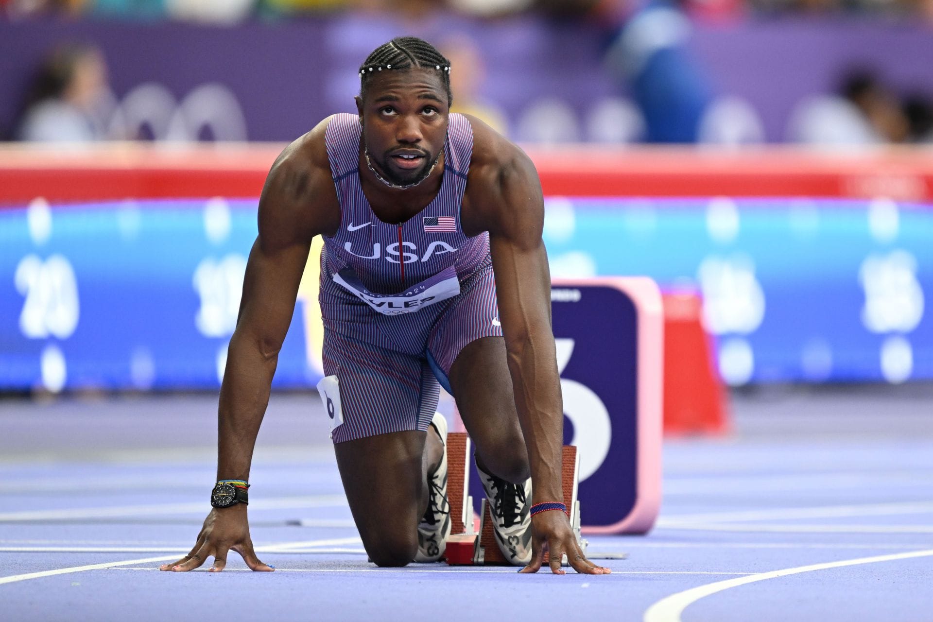 Noah Lyles in a contextual photograph: Contextual starting-block photograph showing race preparation; the uniform covers his torso and it does not show tattoo evidence.; not tattoo evidence