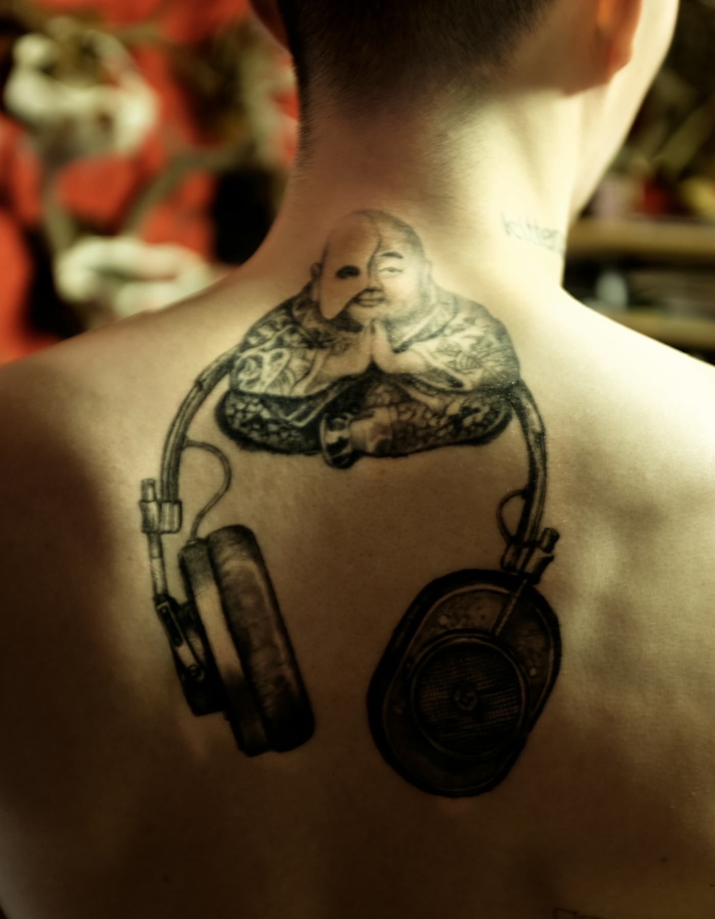 Noma Han tattoos: Buddhist figure and surrounding back tattoo detail
