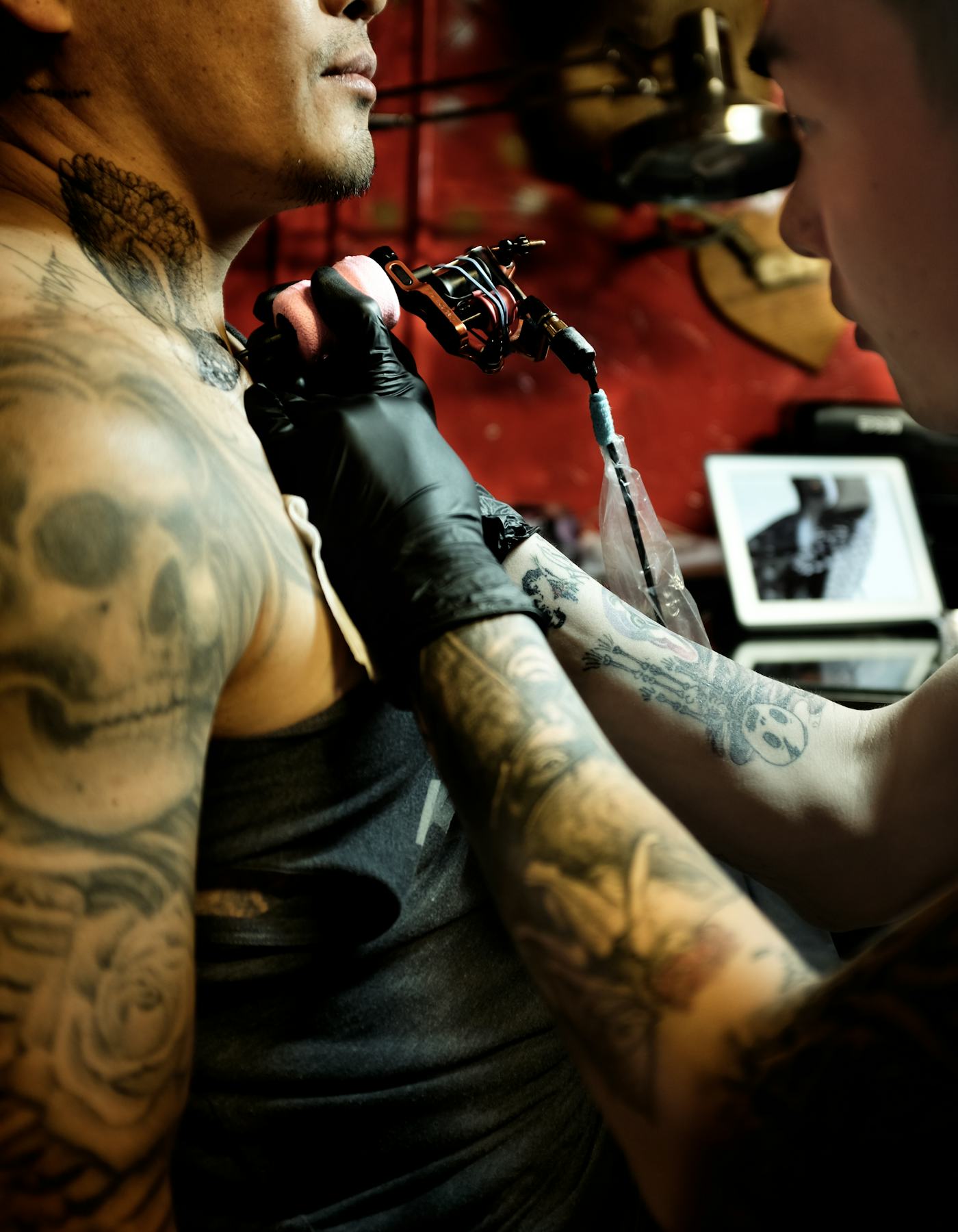 Noma Han tattoos: Layered sleeve and neck tattoos shown during a tattoo session