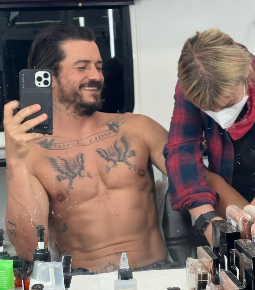 Orlando Bloom tattoos: paired bird chest tattoos with curved banner