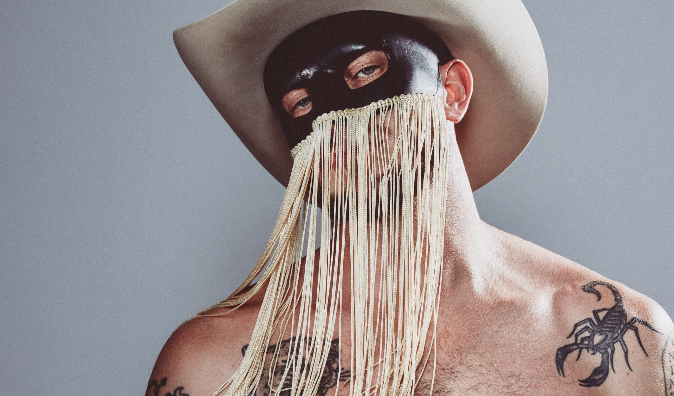 Orville Peck tattoos: shoulder detail showing the golden orb spider