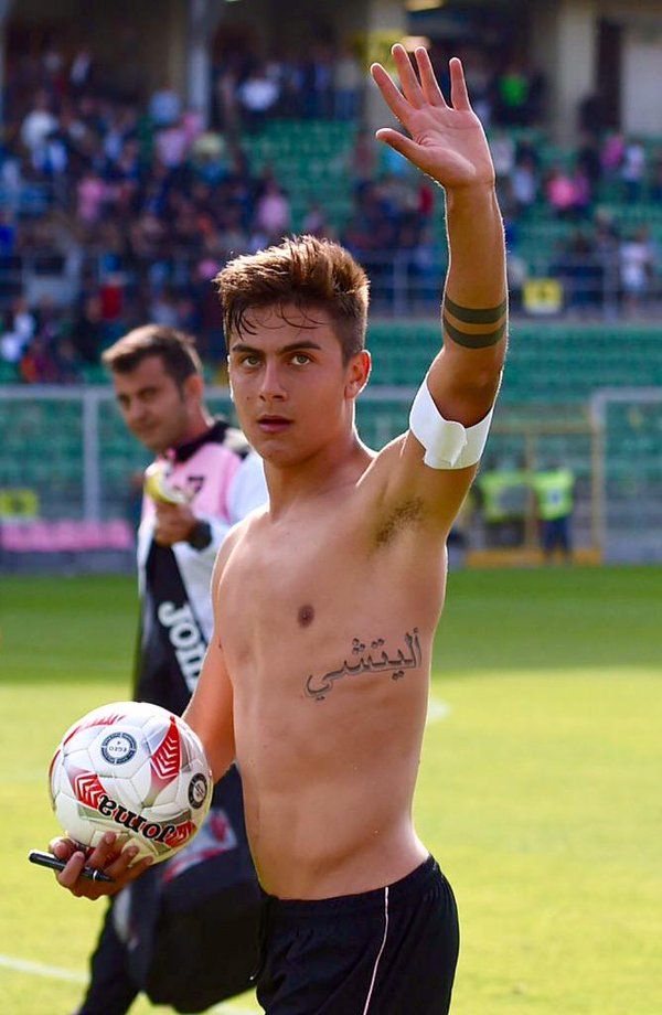Paulo Dybala tattoos: side-on football photograph where the Arabic rib tattoo and double armband are easy to read