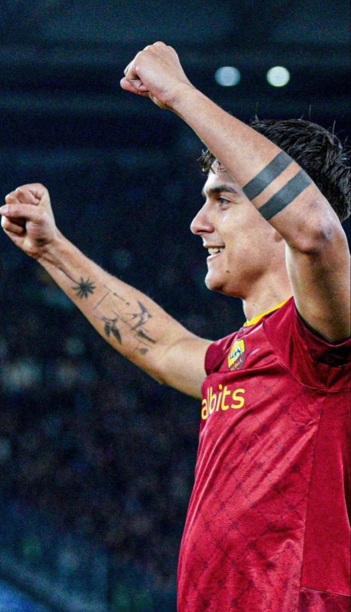 Paulo Dybala tattoos: profile celebration showing the double black bands, bird and star details across the forearms