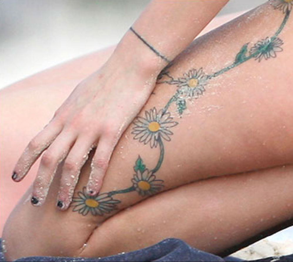 Peaches Geldof tattoos: high-resolution close view of the daisy chain flowers, vine, and hand placement across the leg