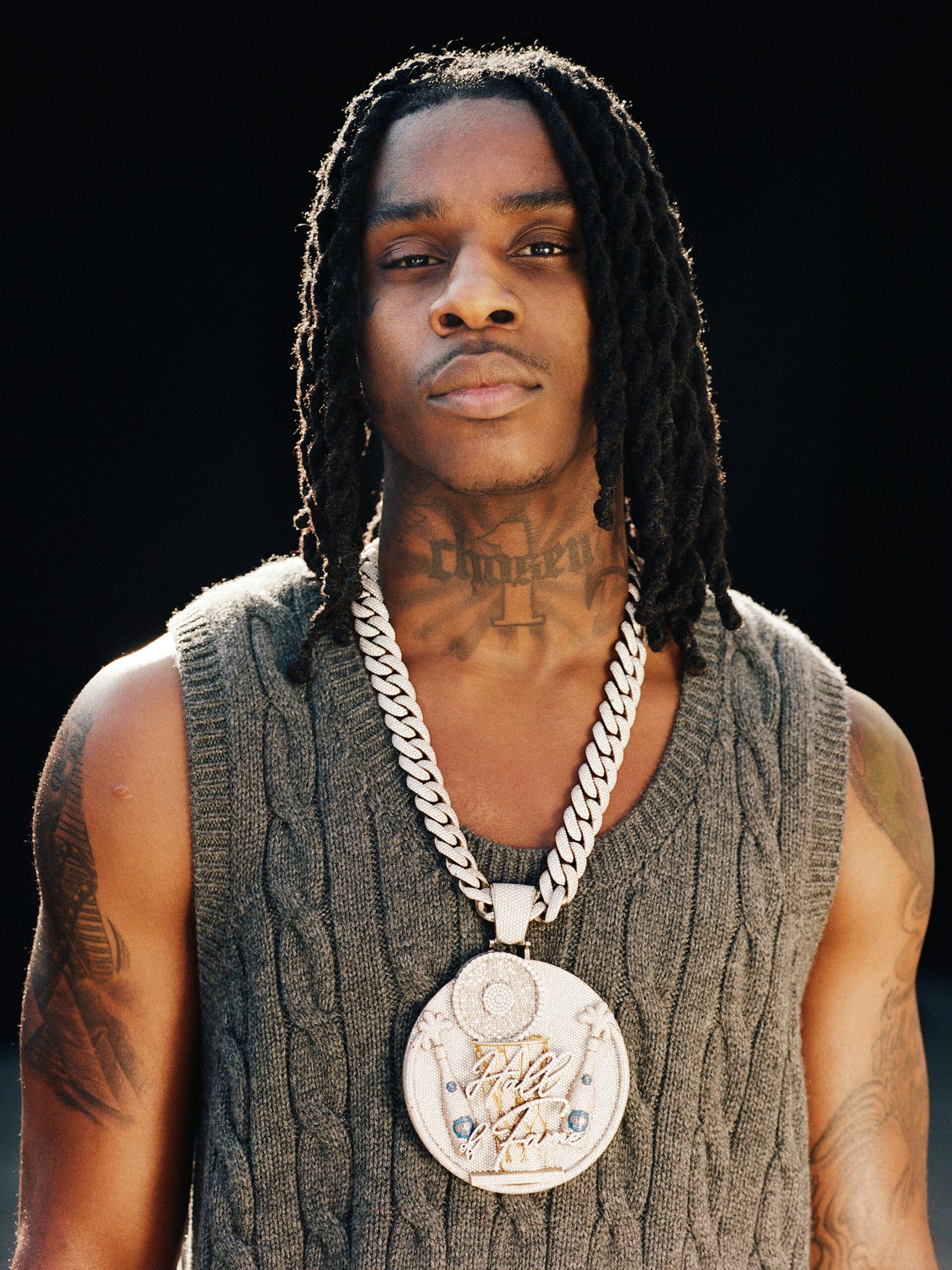 Polo G showing his neck and shoulder tattoos in a close portrait