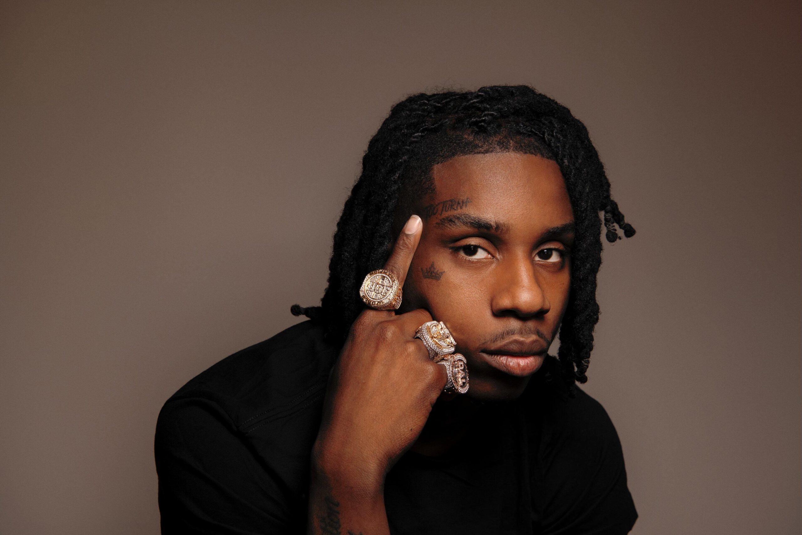 Polo G showing his TOO TURNT forehead tattoo and cheek crown