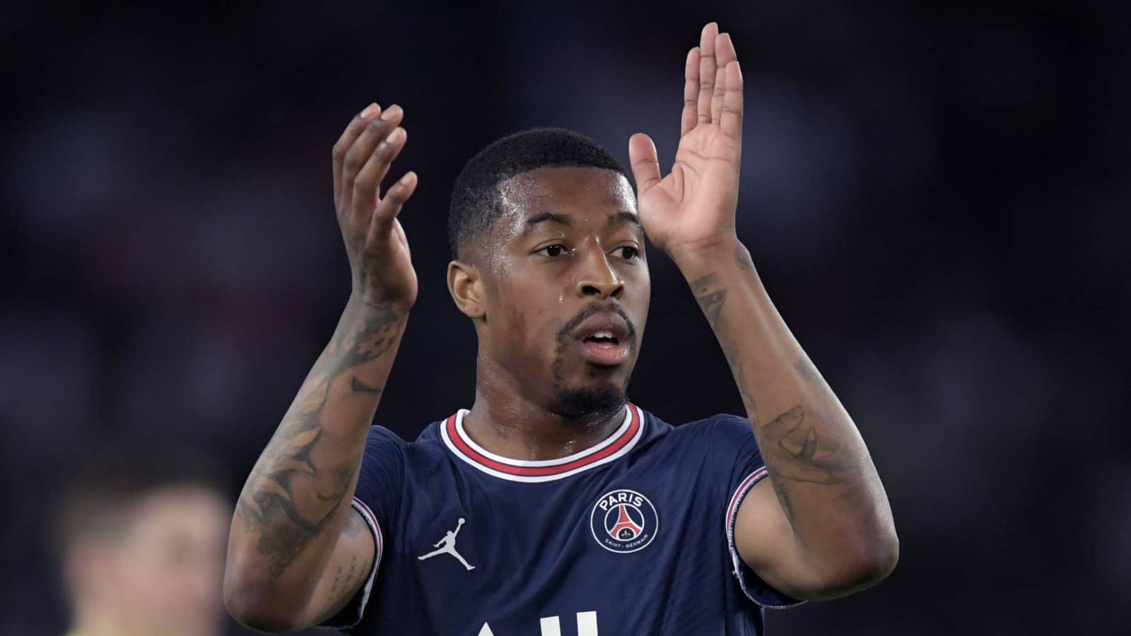 Presnel Kimpembe tattoos: Match photograph showing both tattooed forearms and upper arms while Kimpembe applauds