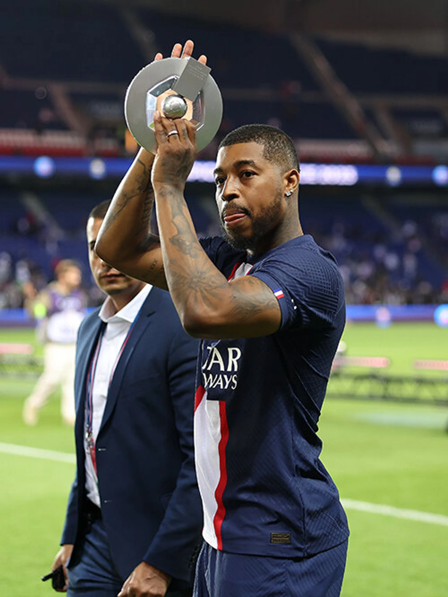 Presnel Kimpembe tattoos: Portrait-format trophy photograph showing the forearm and upper-arm tattoos from a closer angle