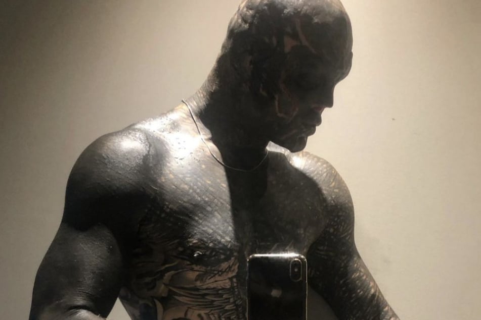 Anthony Loffredo tattoos: mirror photograph showing the blackout torso, patterned chest, tattooed arms and hand details