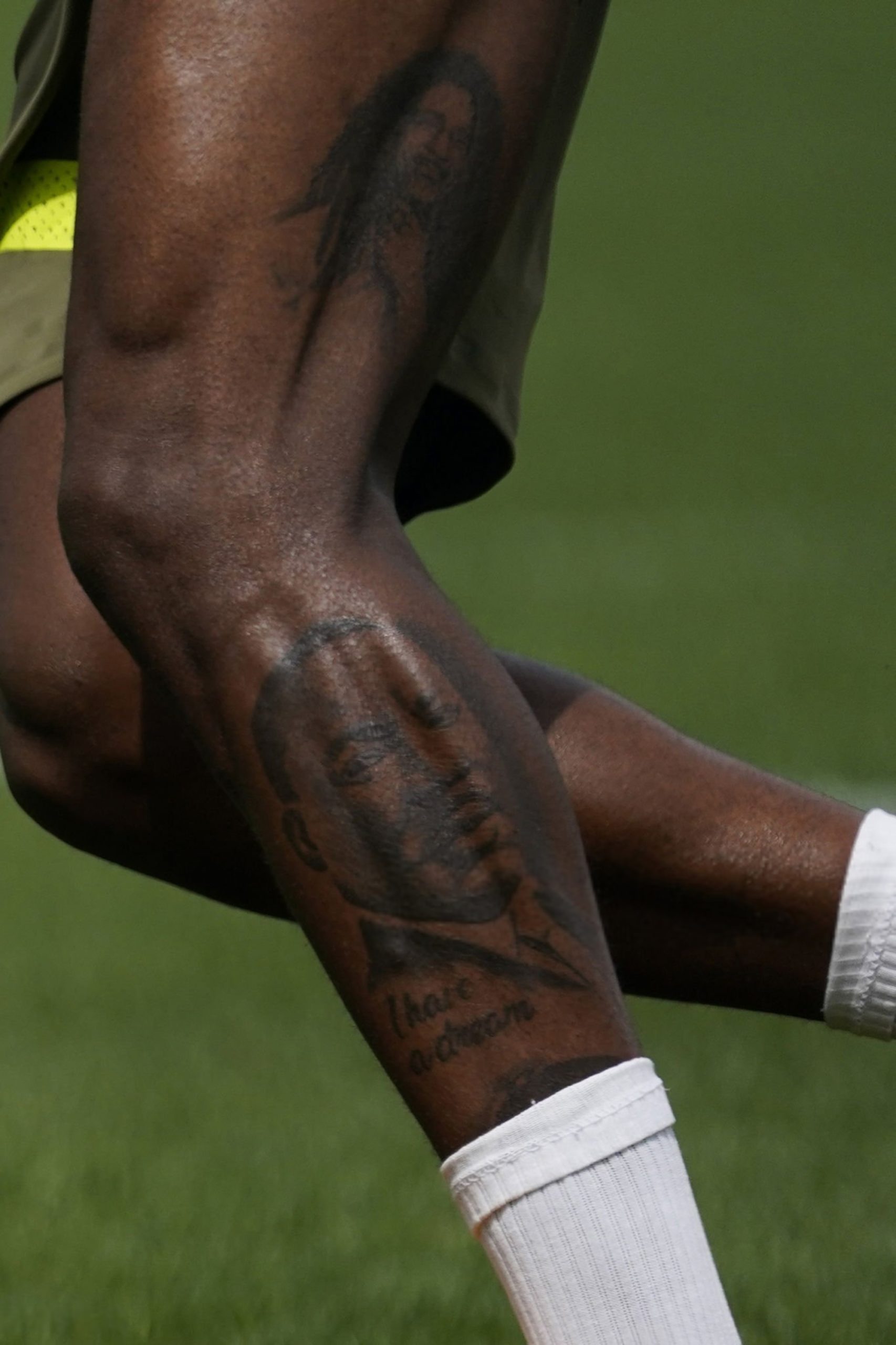 Rafael Leao tattoos: Close editorial photograph showing the Martin Luther King portrait and quotation on Leão’s calf