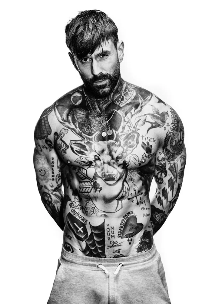 Ricki Hall tattoos: clean full-body studio portrait showing the complete front layout, large central image and smaller lettering around it