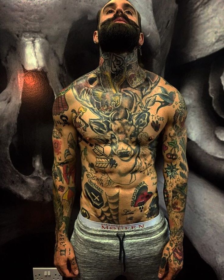 Ricki Hall tattoos: color portrait showing the old-school chest, arm and hand pieces clearly against a dark skull mural