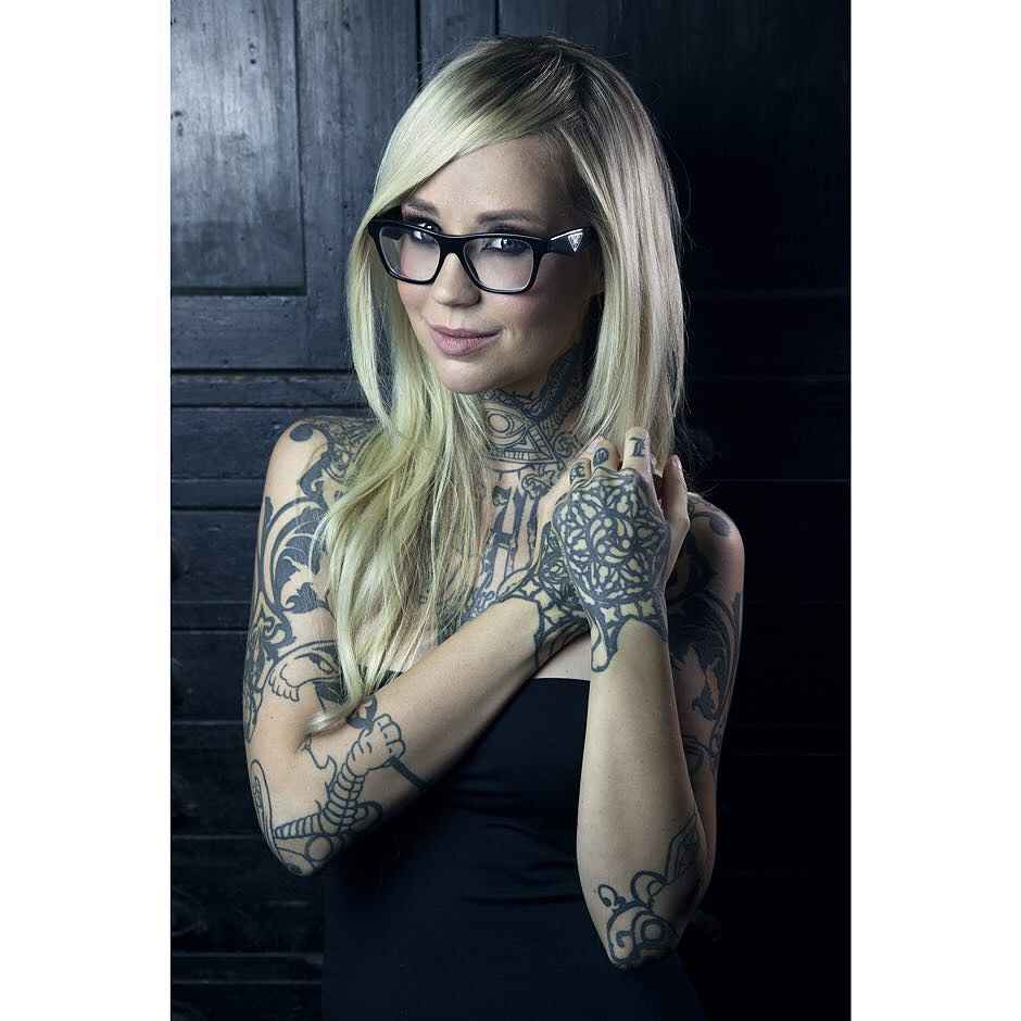 Sara Fabel tattoos: Interlocking black pattern on back of hand, with open loops and defined border.