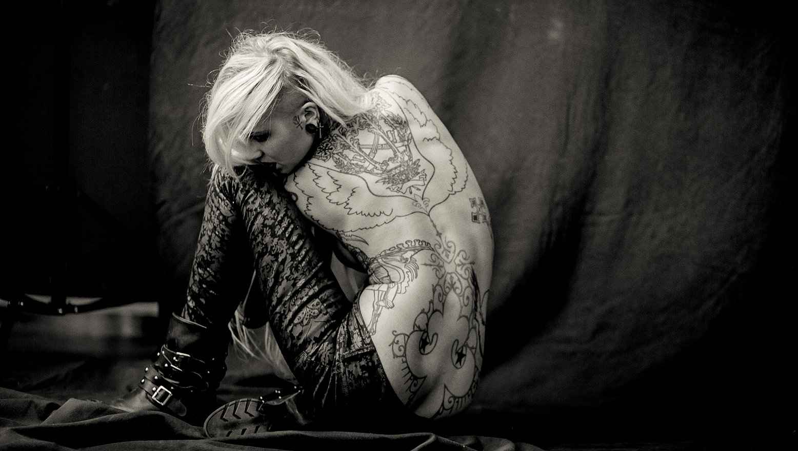 Sara Fabel tattoos: Lower back figure and long ornamental curls visible in a separate horizontal photograph.