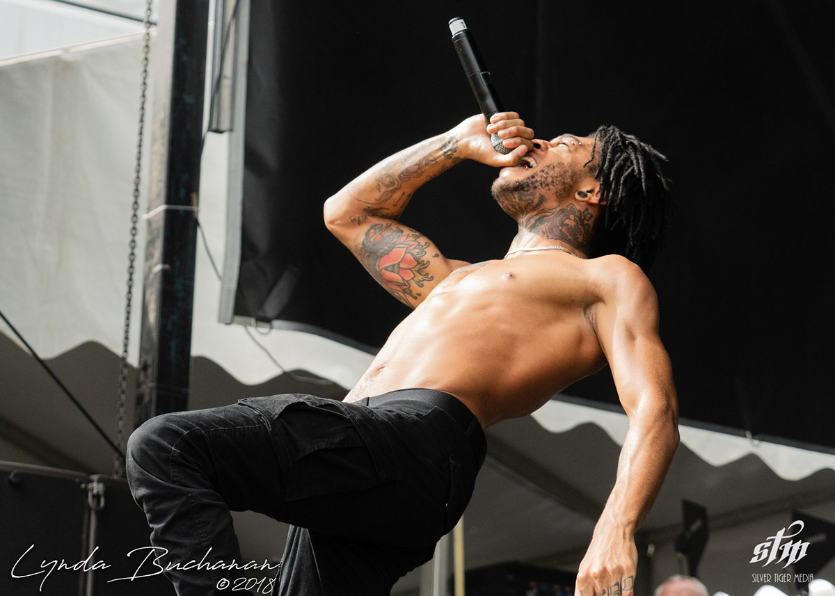 Scarlxrd tattoos: high-resolution stage portrait showing the tattooed forearms, hand and neck work