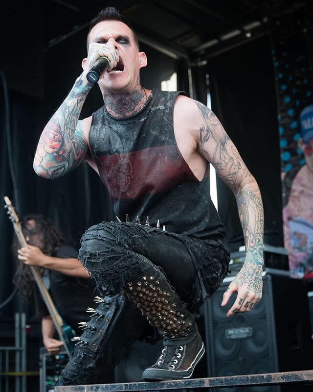 Scott Lewis showing his arm and neck tattoos while singing