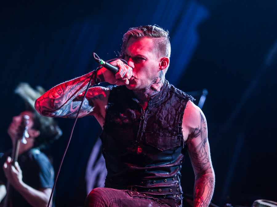 Scott Lewis showing tattoos on both arms at a concert