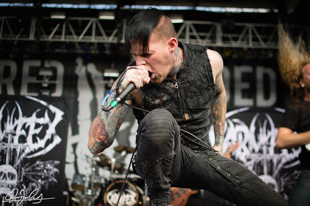 Scott Lewis showing colorful forearm tattoos during a live show