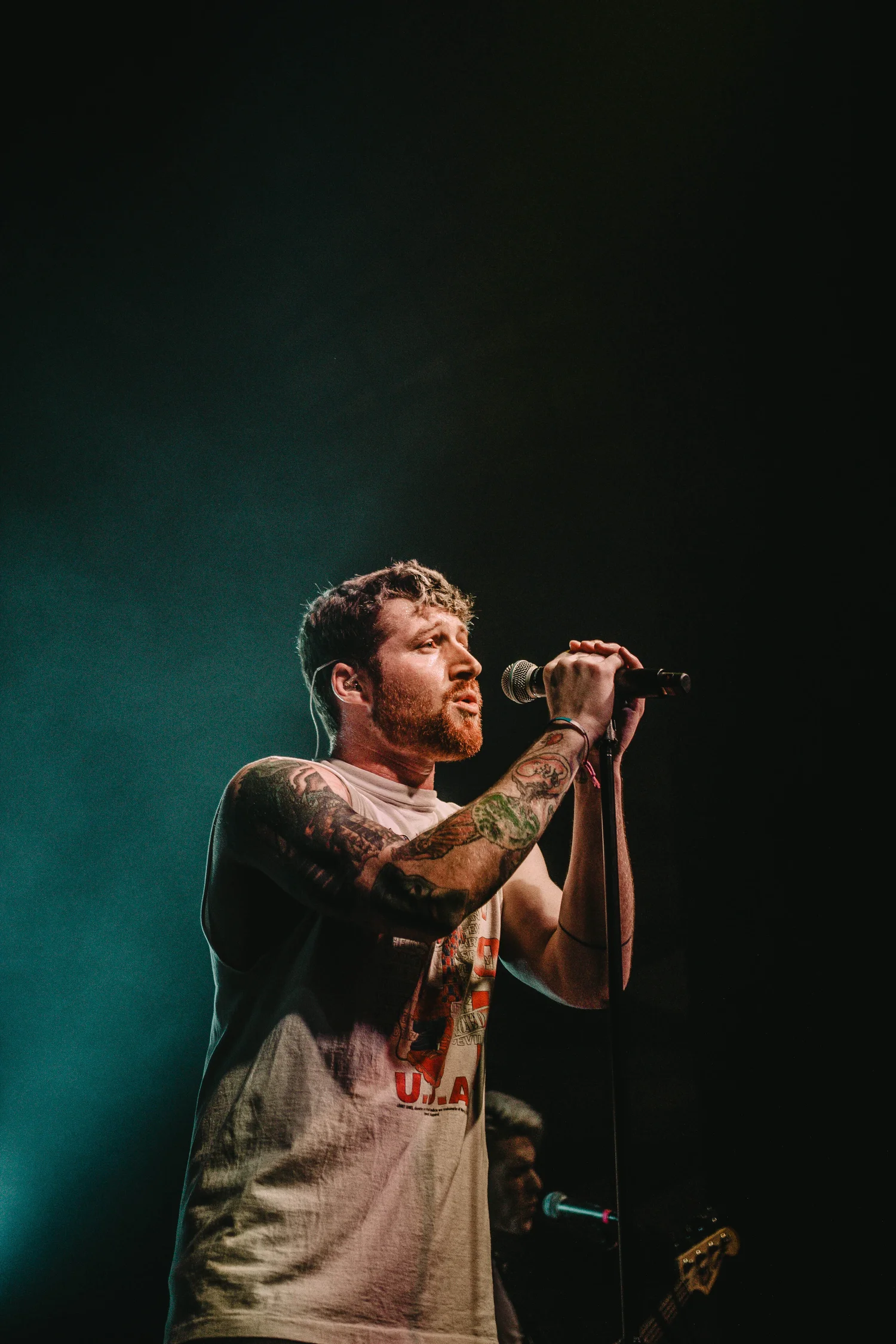 Scotty Sire tattoos: Tattoo evidence: live tour photograph showing both tattooed arms in a distinct performance setting.