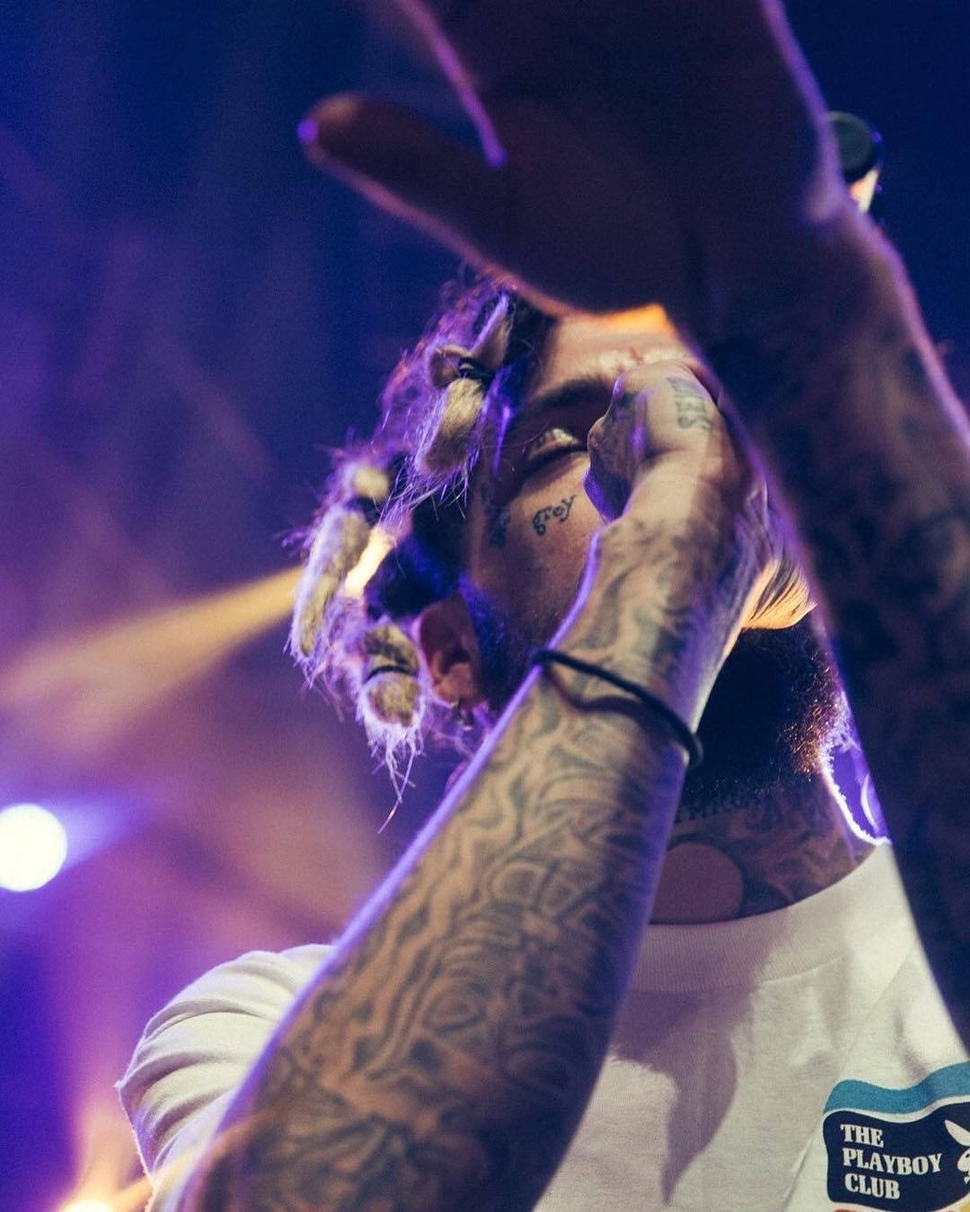 Scrim tattoos: a live performance close-up showing the arm, shoulder and visible body ink