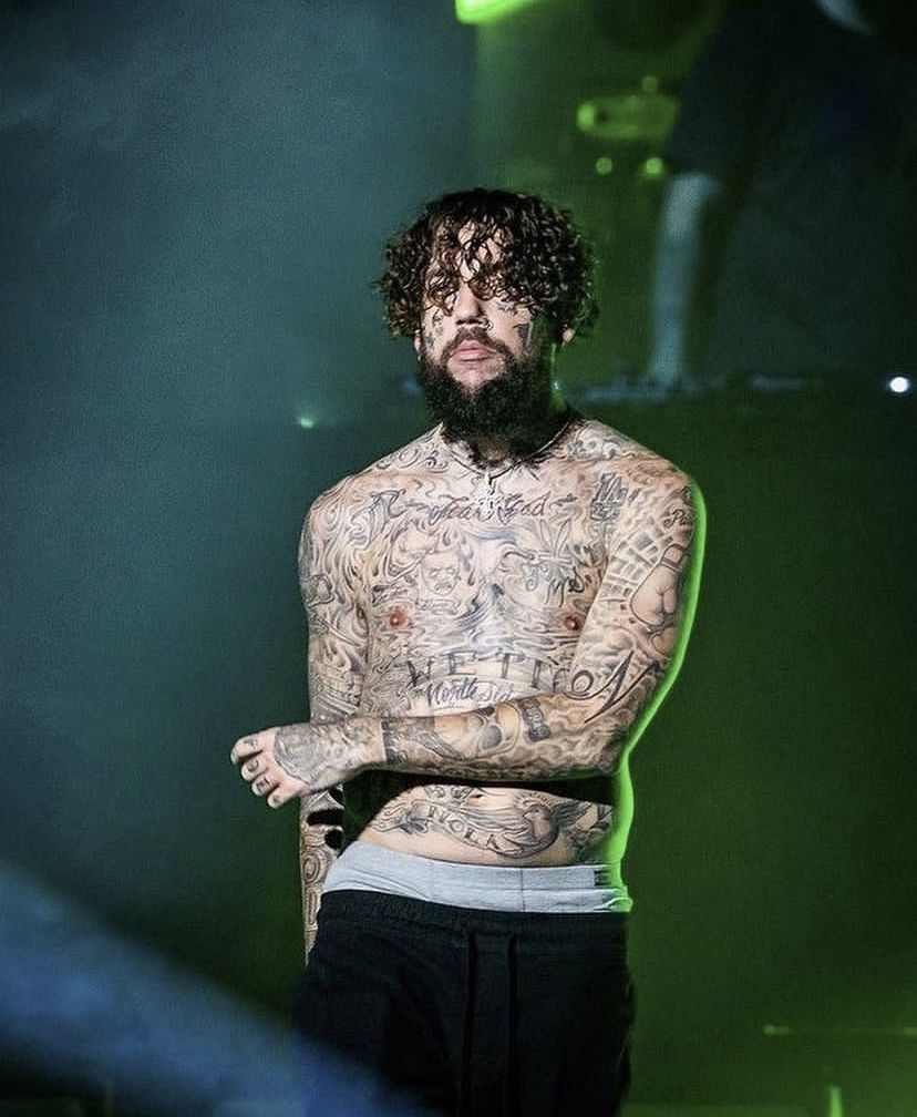 Scrim tattoos: a shirtless performance portrait showing the chest, stomach and both tattooed arms