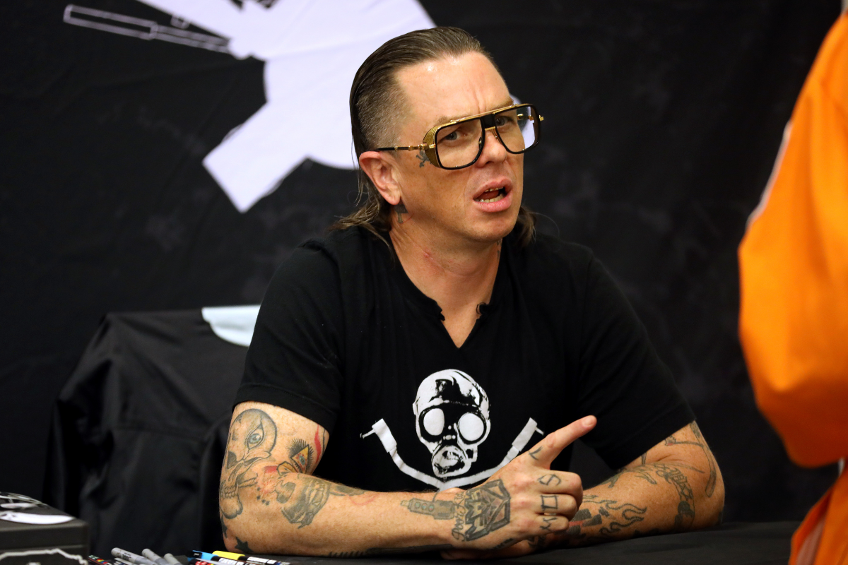 Sid Wilson tattoos: high-resolution fan-event portrait showing both tattooed forearms, hands and neck