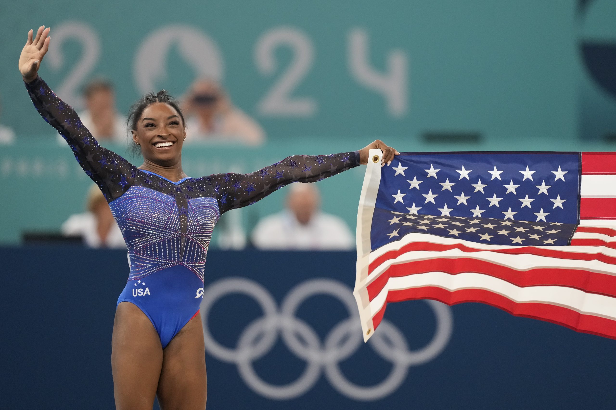 Simone Biles contextual medal celebration with team flag; does not show tattoo evidence Simone Biles in a contextual photograph: contextual medal celebration with team flag; does not show tattoo evidence; not tattoo evidence