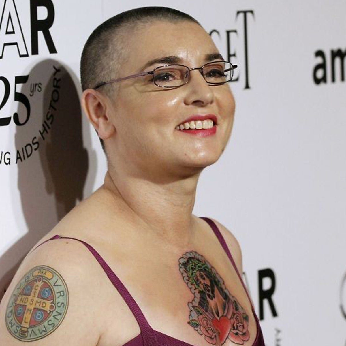 Sinéad O'Connor tattoos: Sinéad O'Connor arm script and chest tattoo, selected because the named tattoo area is clearly visible in a distinct high-resolution photograph