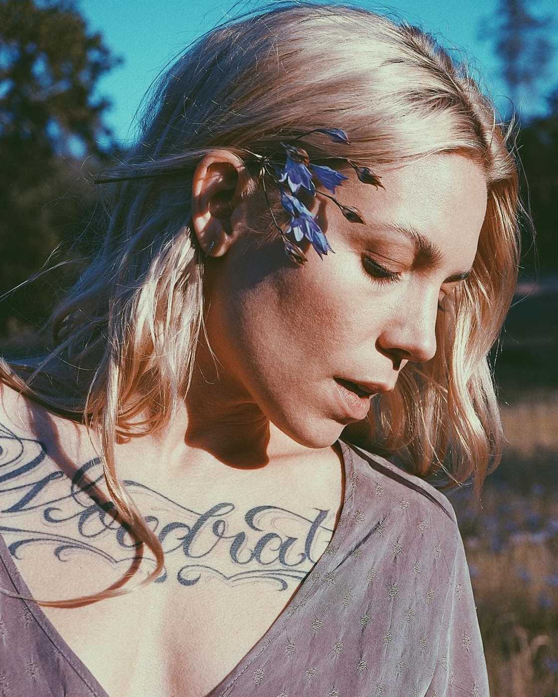 Skylar Grey tattoos: Large chest-script photograph; the visible Woodrat lettering and adjoining shoulder ink are clear
