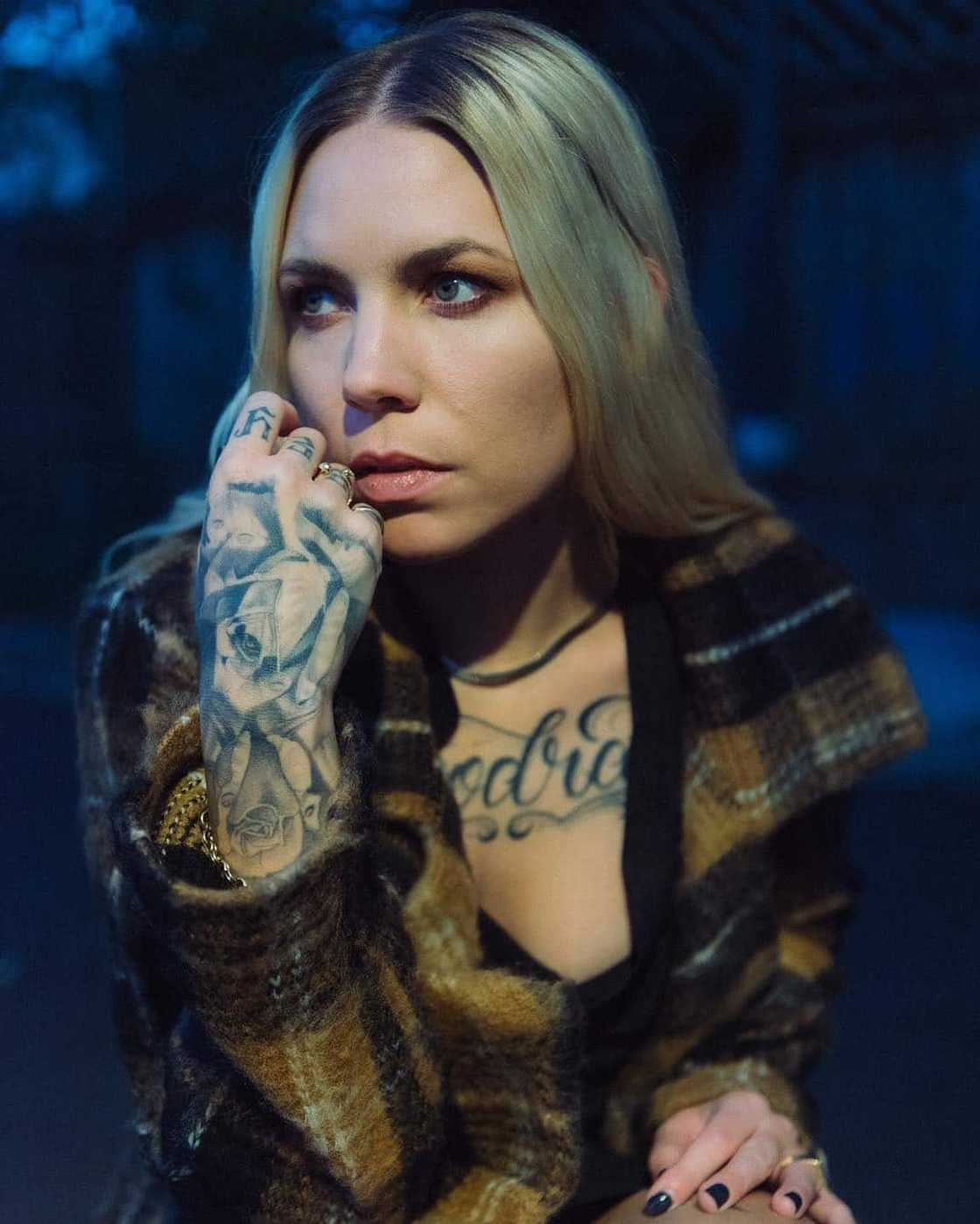 Skylar Grey tattoos: Plaid portrait showing dense hand and forearm tattoo work alongside chest lettering