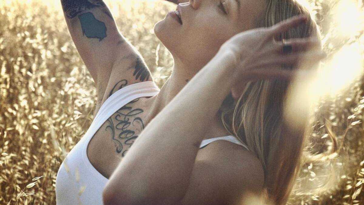 Skylar Grey tattoos: Wide outdoor profile showing chest script and arm tattoos in a distinct composition