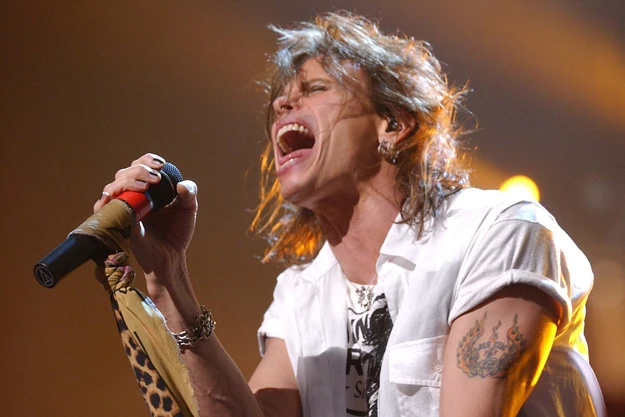 Steven Tyler Ma Kin tattoo visible on his upper arm during a live Aerosmith performance