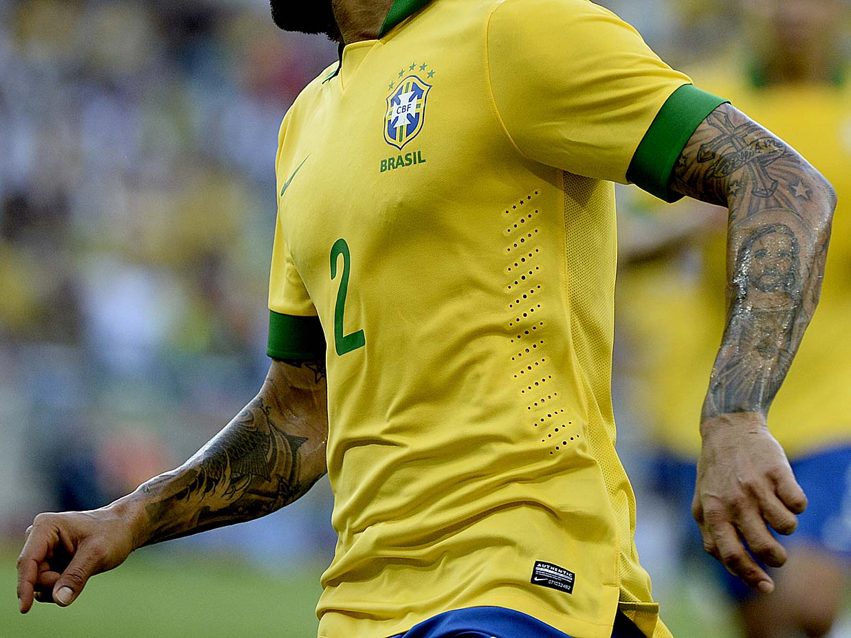 Dani Alves tattoos: sharp close photograph of Dani Alves showing the religious arm tattoos, cross work and detailed sleeve linework