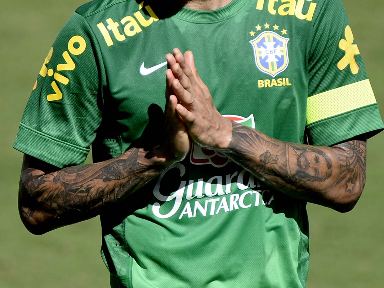 Dani Alves tattoos: separate sharp photograph showing the flower, lettering and layered forearm work while Alves drinks from a bottle