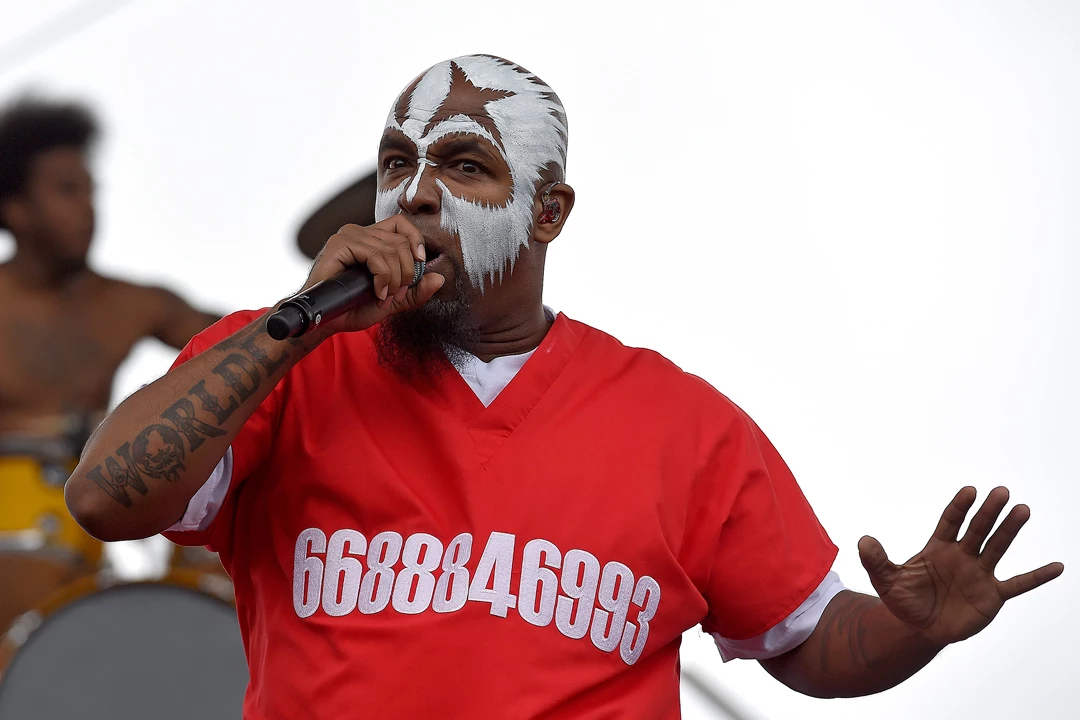 Tech N9ne tattoos: stage portrait showing the bold arm lettering under face paint and concert lighting
