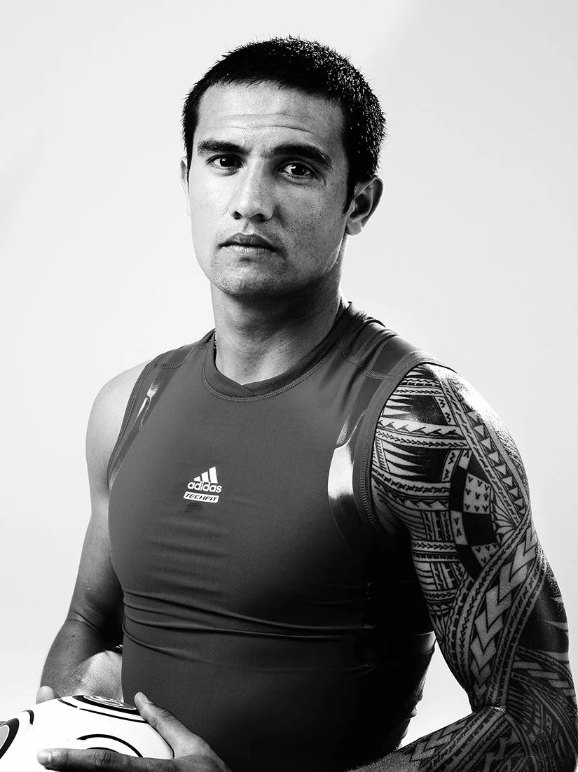 Tim Cahill Distinct black-and-white studio view showing Cahill's face and the geometric left-arm sleeve clearly Tim Cahill tattoos: Distinct black-and-white studio view showing Cahill's face and the geometric left-arm sleeve clearly