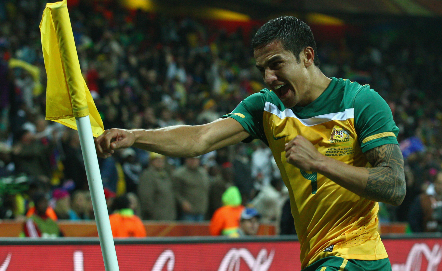 Tim Cahill Separate green-and-gold corner-flag celebration frame with the sleeve visible on his left arm Tim Cahill tattoos: Separate green-and-gold corner-flag celebration frame with the sleeve visible on his left arm